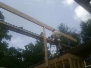 Carpenter setting a ridge beam over a new addition frame — Ice Dam Removal by Roofing Brothers in Lake City