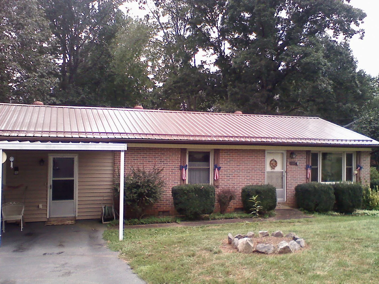 Bronze metal roof and carport on a brick ranch home — Roof Repair work by our crew in Lake City