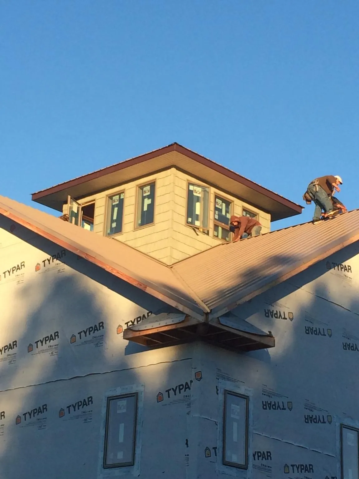 Roofers working around a rooftop cupola on a new metal roof at sunset — Roof Waterproofing in Lake City by Roofing Brothers